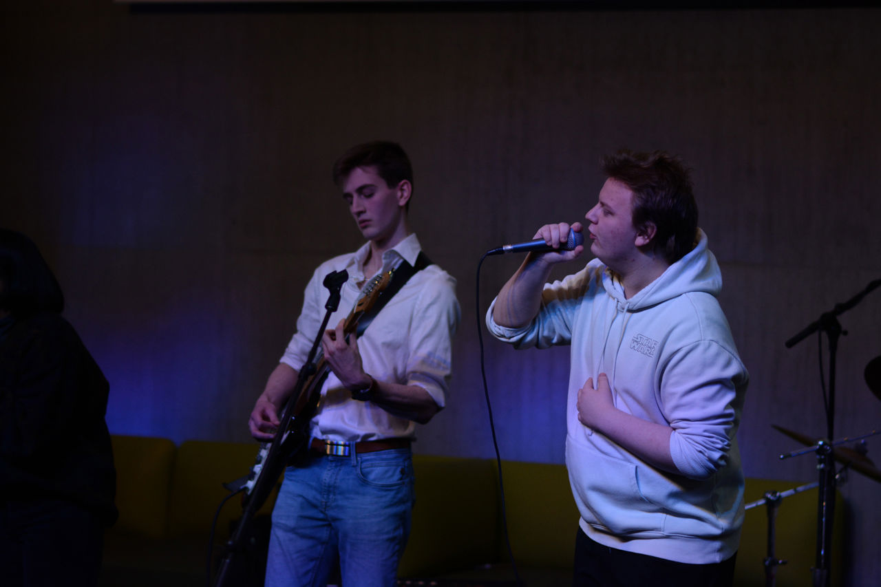Bildet viser to ungdommar som speler gitar og syng.
