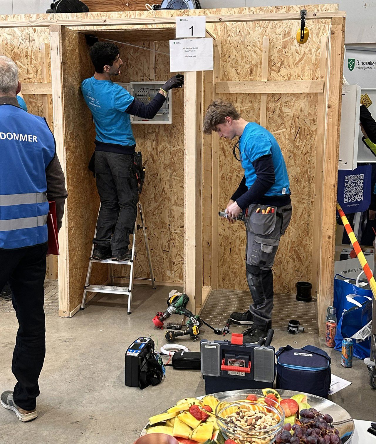 Didar og Lars konsentrerte om arbeidet i "båsen" deira under konkurransen. Ein dommar følger med frå kanten av bildet.