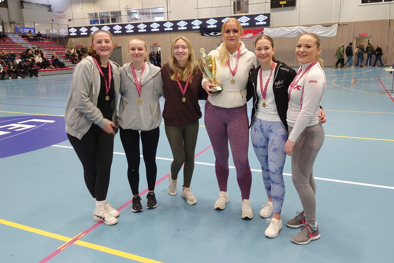 Dei seks jentene på vinnarlaget frå 3PBYc, arm i arm, med gullmedaljar rundt halsen. Abelone, i midten, held vandrepokalen.