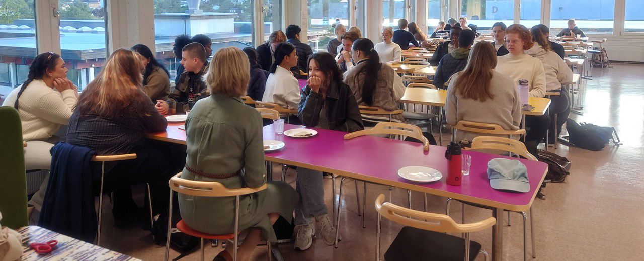 Elevar rundt frukostbordet, saman med vertskapet frå elevtenesta.