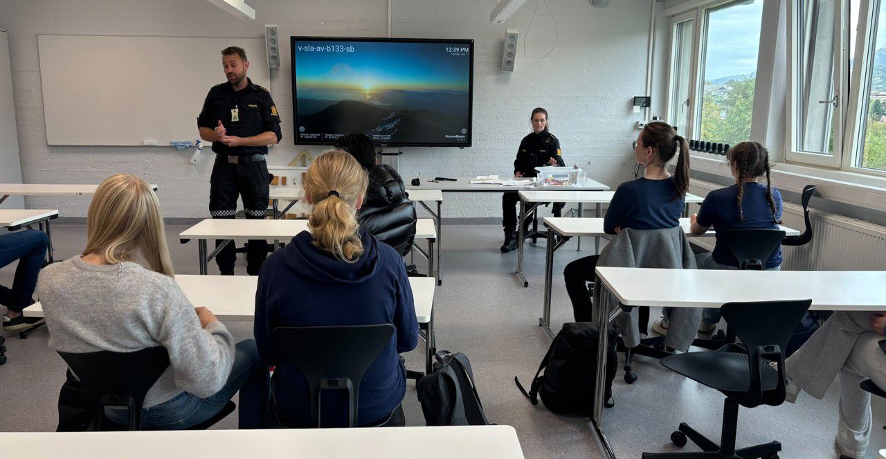 To politibetjentar snakkar til ei gruppe elevar i eit klasserom.