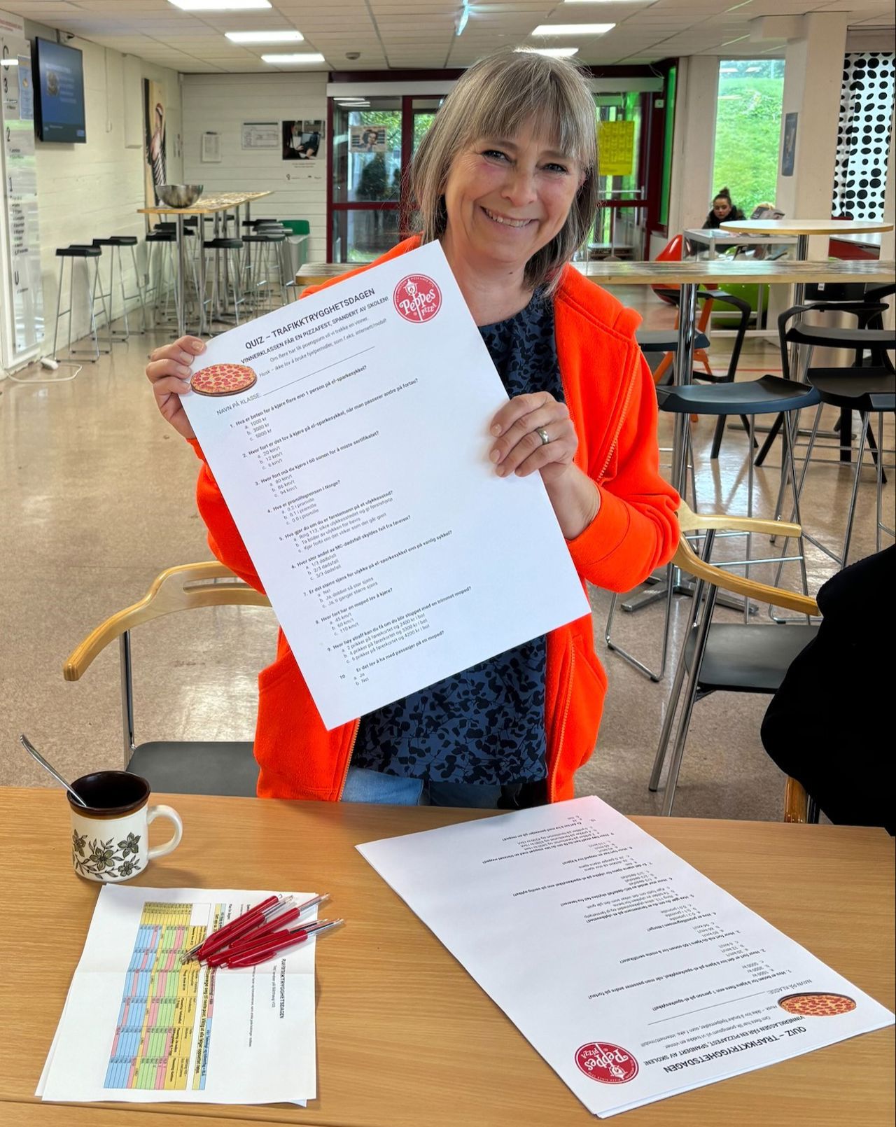 Renate frå elevtenesta held opp eit ark med quiz-spørsmål.