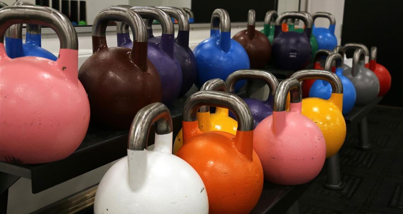 Eit stativ med kettle bells i ulike fargar.