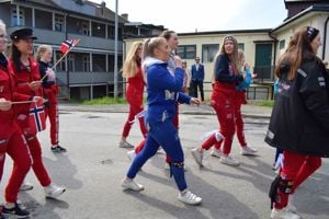 Ei gruppe russ, raude og blå, marsjerer forbi på vegen